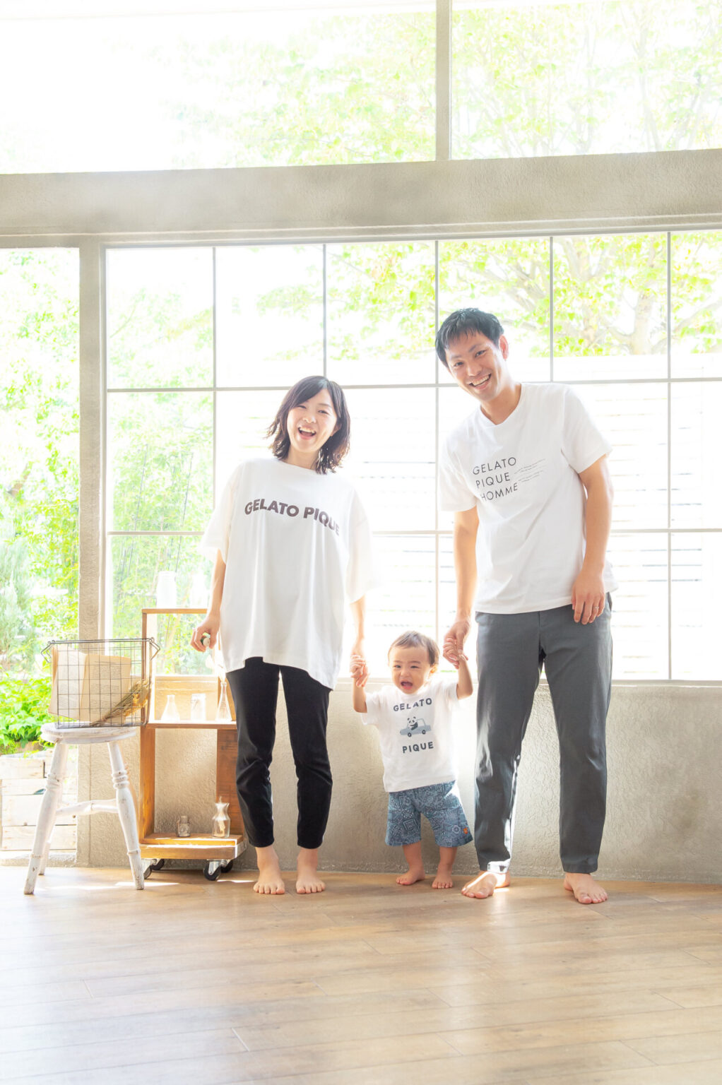 窓辺で手をつないで立つ親子3人