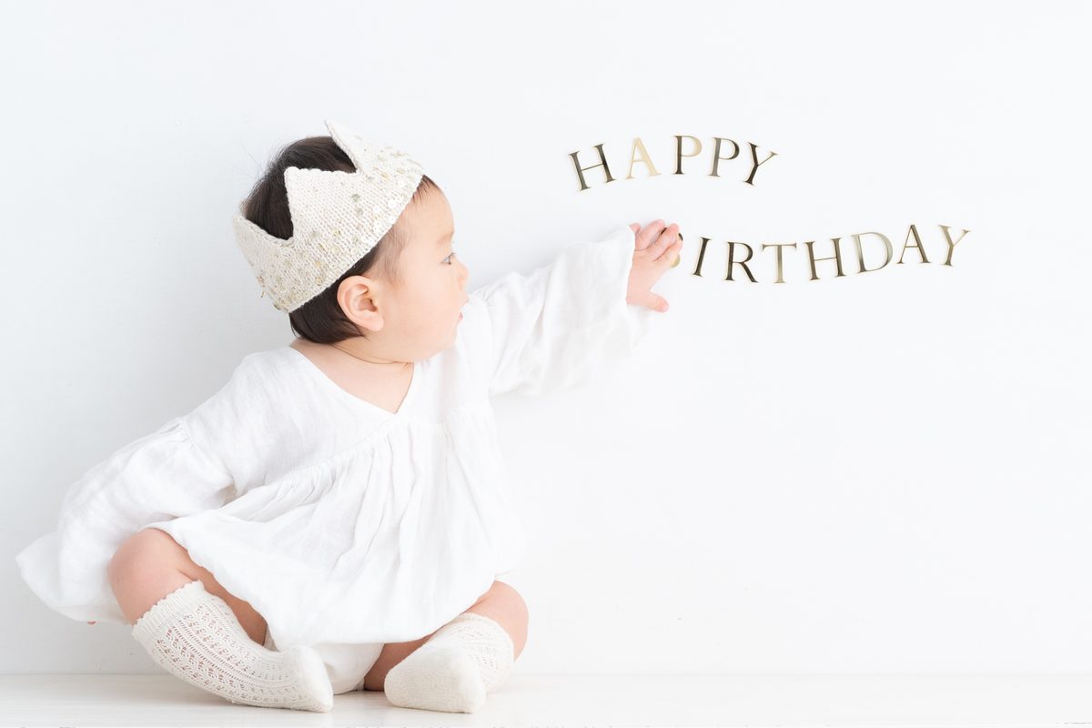 HAPPY BIRTHDAYの文字の前で笑う男の子