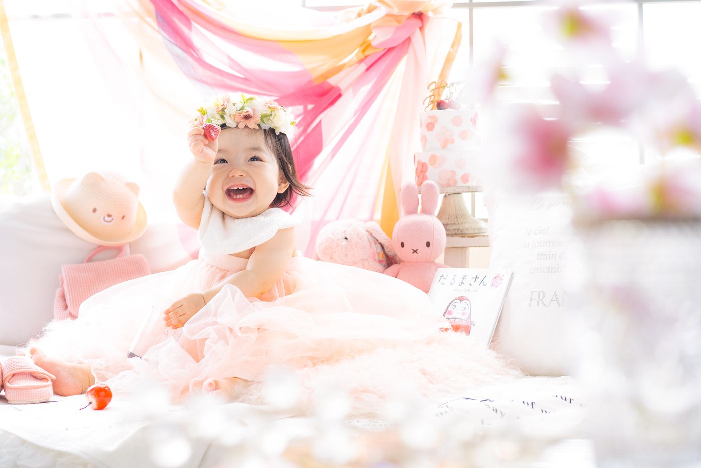 ピンクの飾りつけの中で笑う1歳の女の子