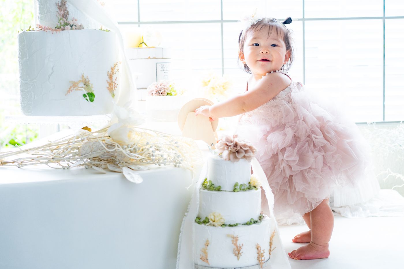 ピンクのドレスでケーキの横に立つ女の子