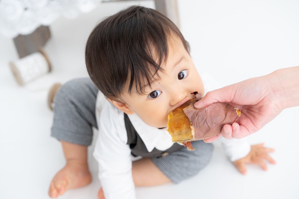 ママの手からおやつをほおばる男の子
