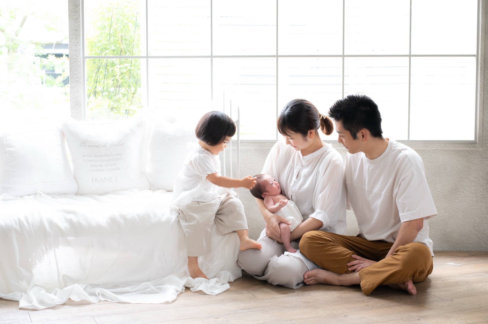 窓辺で新生児を囲む家族