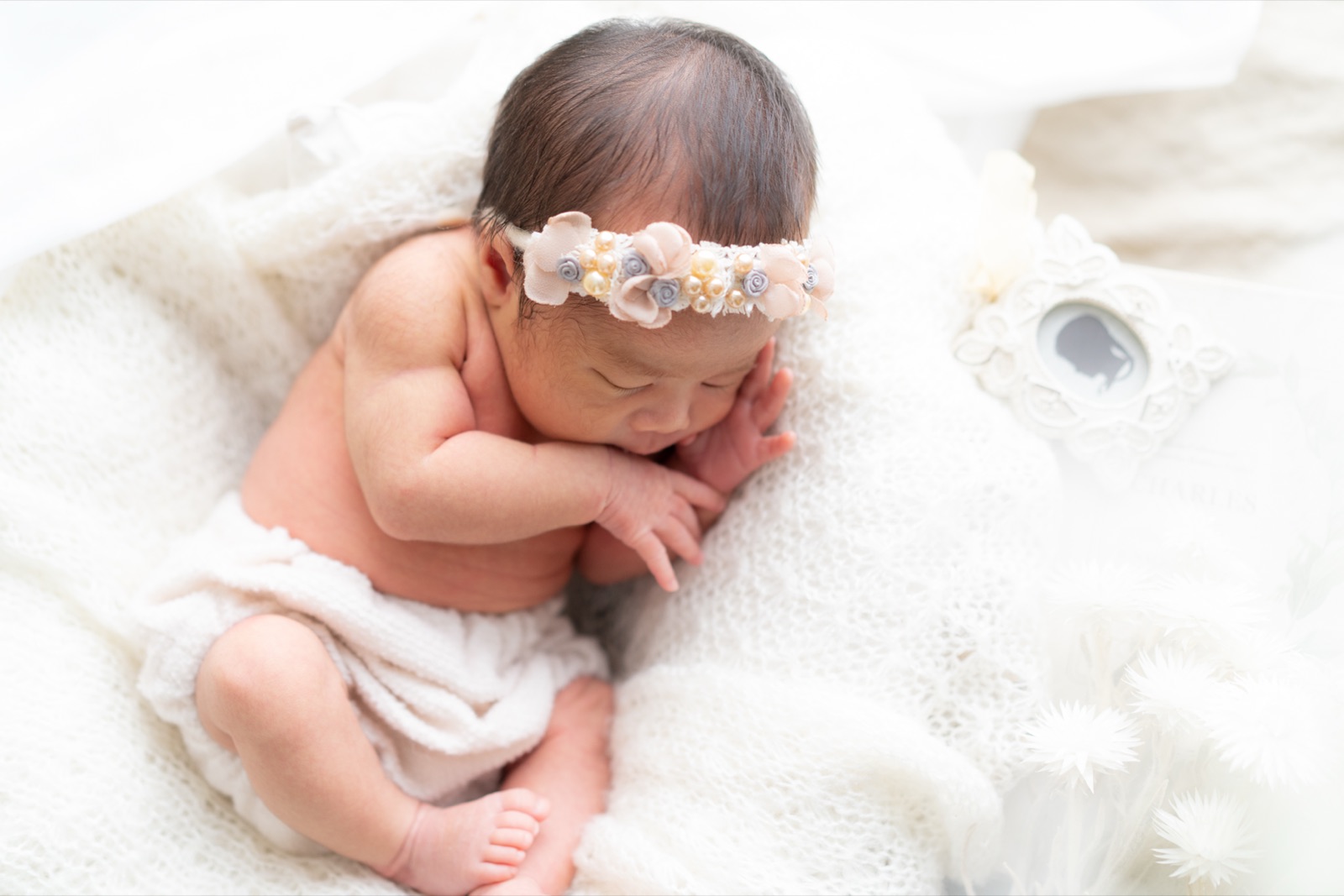 花のヘアバンドをつけて眠る新生児