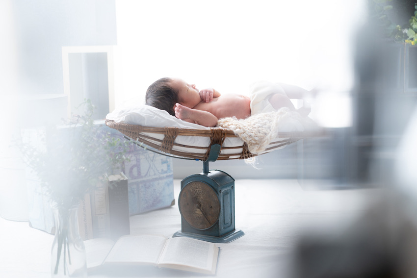 アンティークのスケールの上で眠る新生児