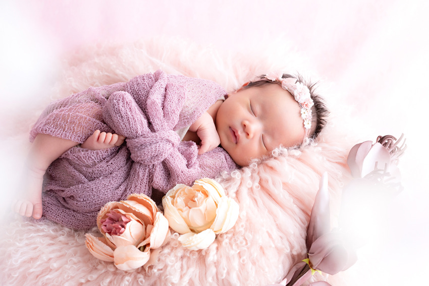 ラベンダー色のおくるみで眠る新生児