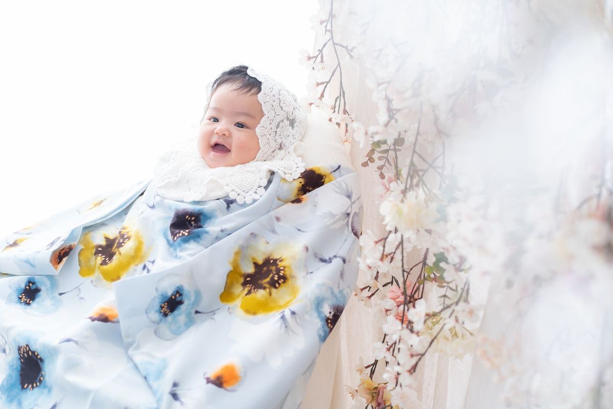水色の花柄の晴れ着とドライフラワーのセットで寝転ぶ赤ちゃん