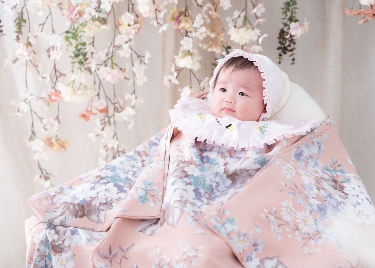 桜のセットで淡いピンクの晴れ着に包まれた赤ちゃん