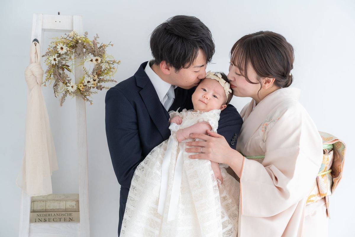 ベビードレスの赤ちゃんにキスするパパとママ