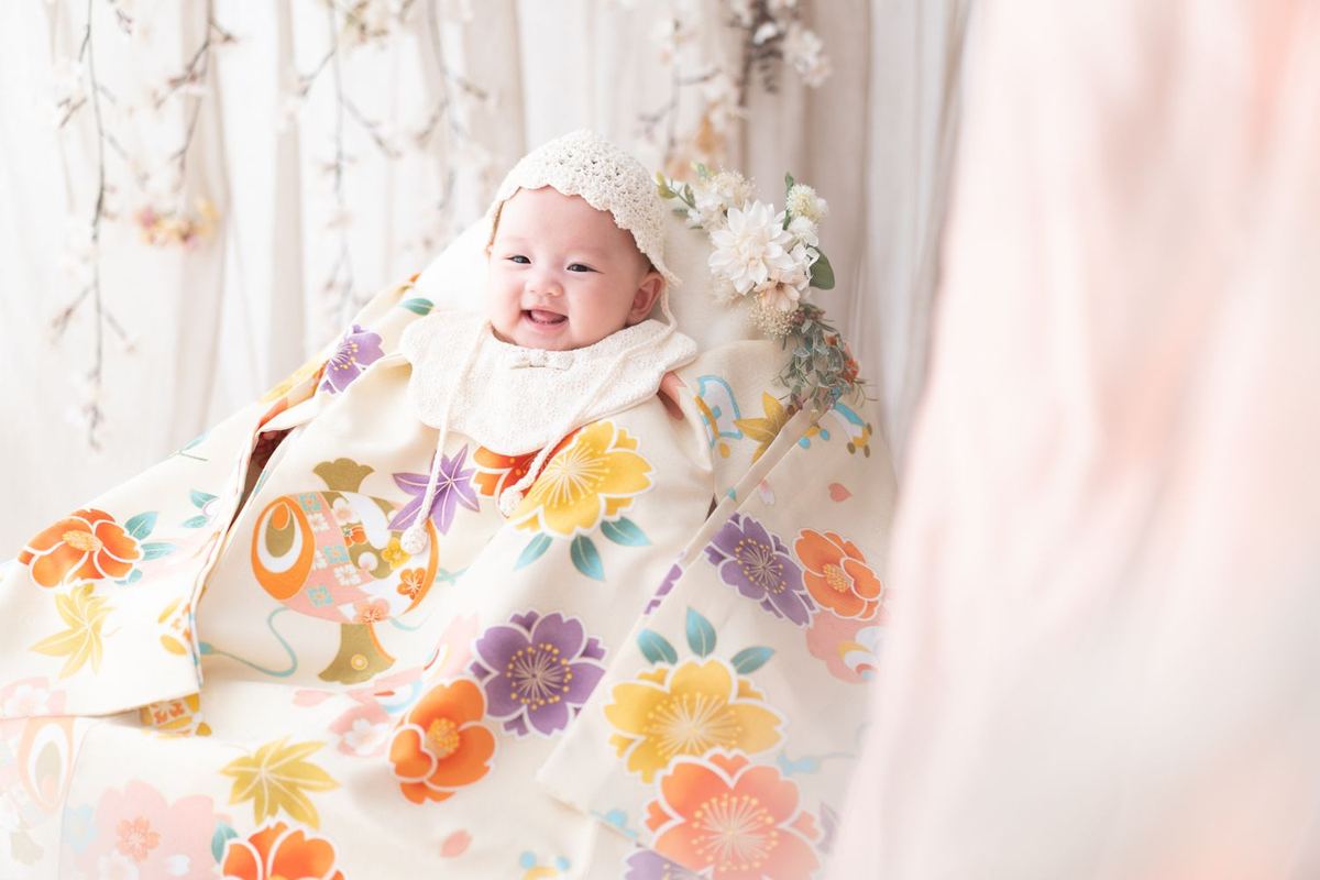 色鮮やかな花柄の晴れ着で笑うお宮参りの赤ちゃん