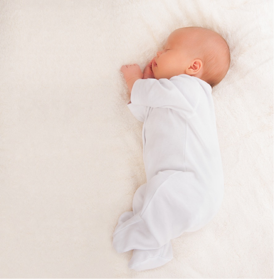 白いベビー服で眠る新生児