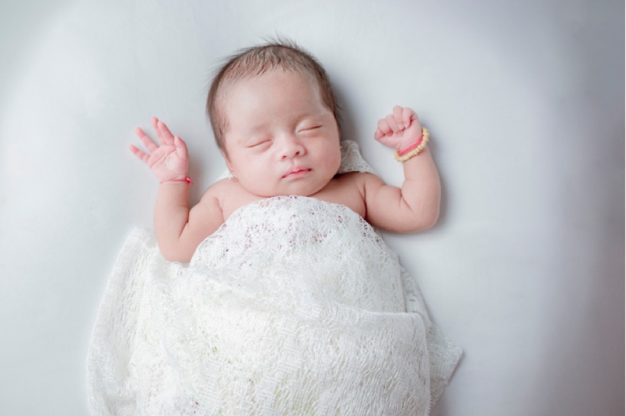 レースのおくるみで眠る新生児