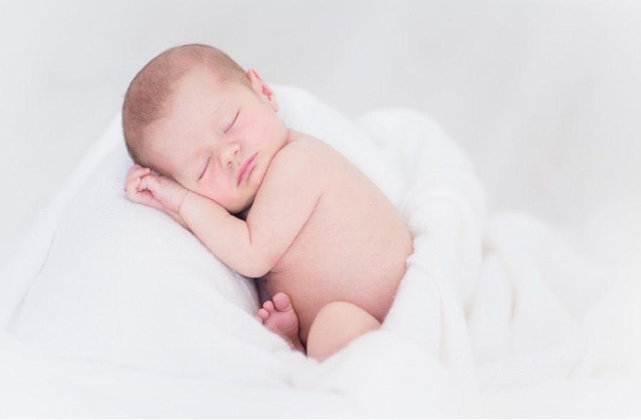 白いブランケットの上で眠る新生児