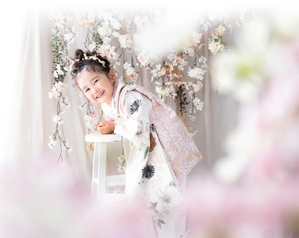 桜の飾りの前で微笑む七五三の女の子