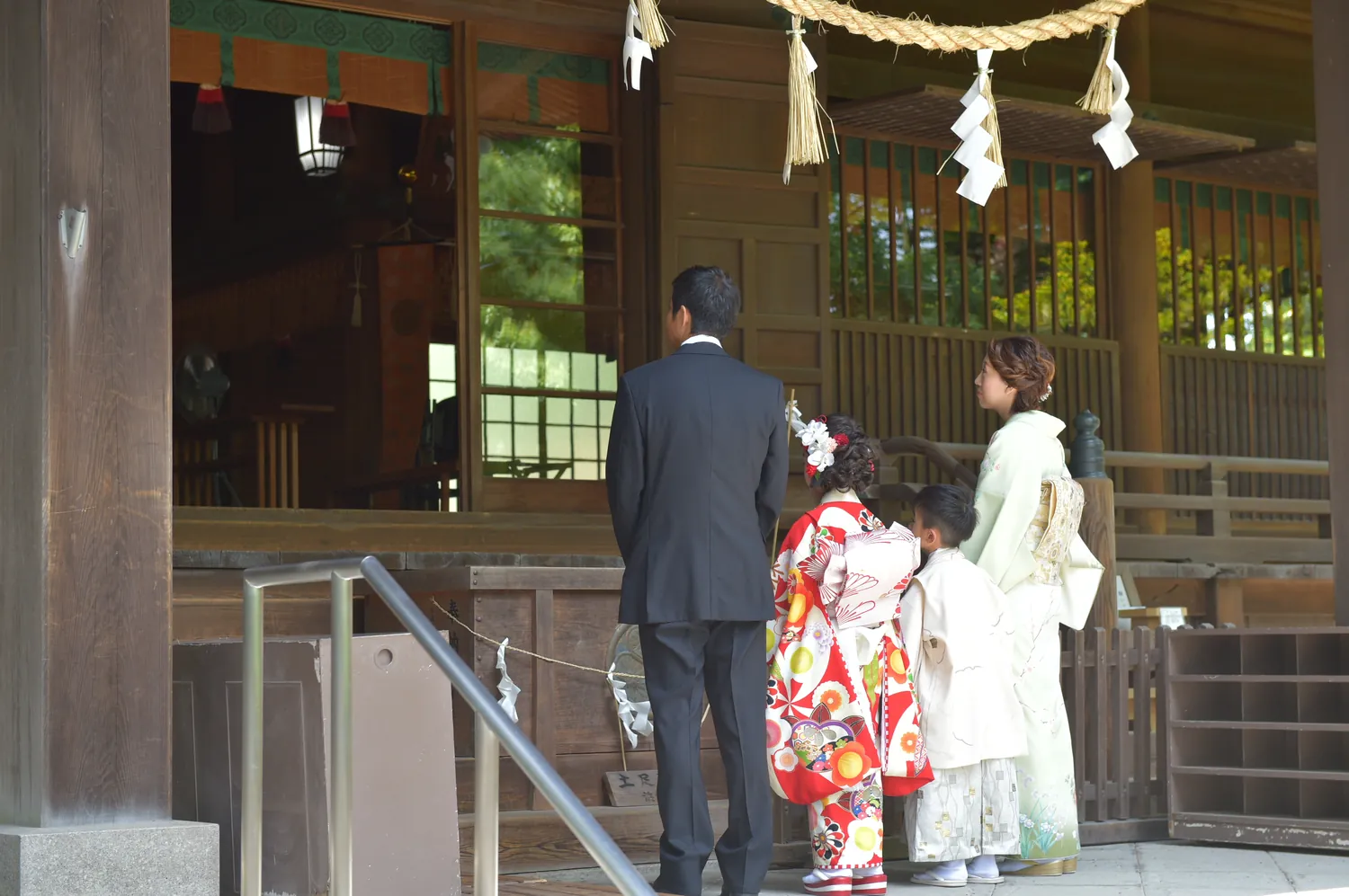 拝殿でお参りする七五三の家族の後ろ姿