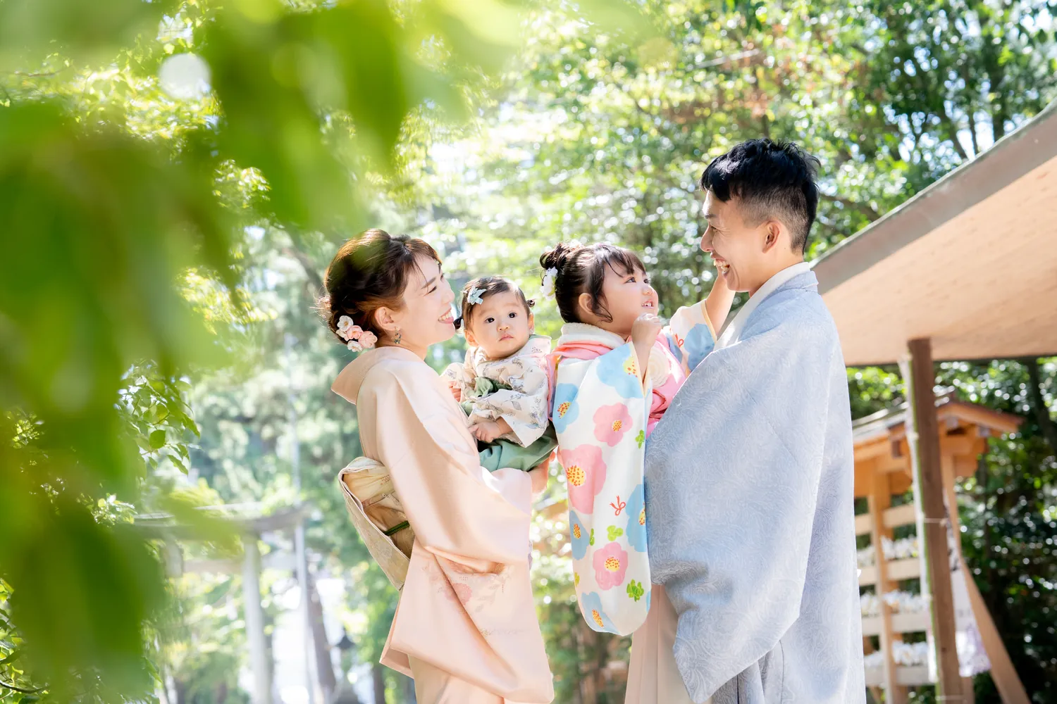 神社の境内で赤ちゃんを抱いた家族と七五三の女の子