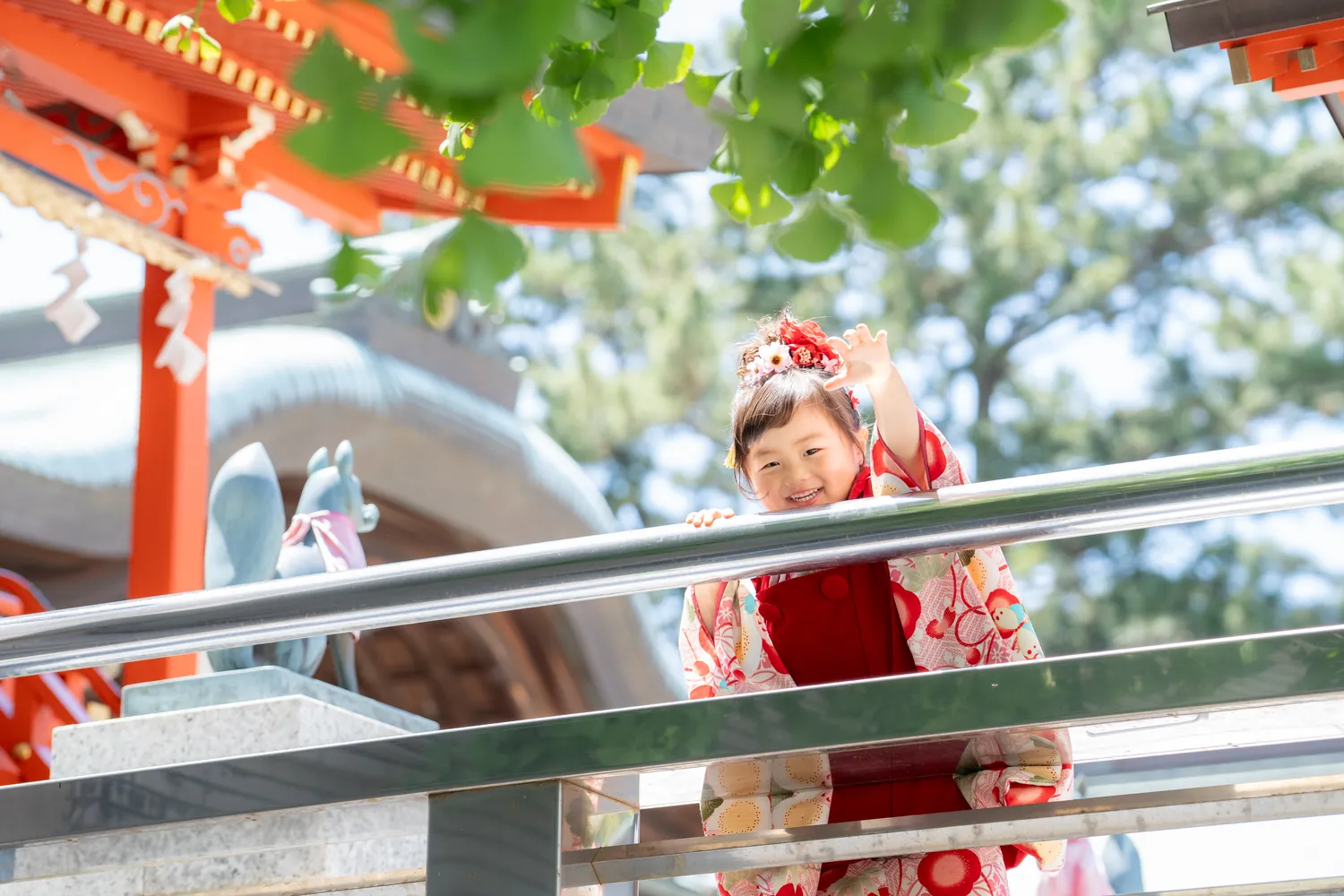 朱色の神社で手を振る七五三の女の子