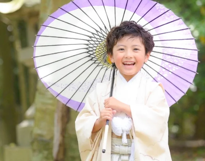 紫の和傘を持って笑う袴姿の男の子