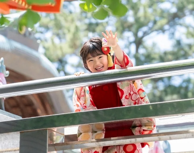 神社の手すりから手を振る七五三の女の子