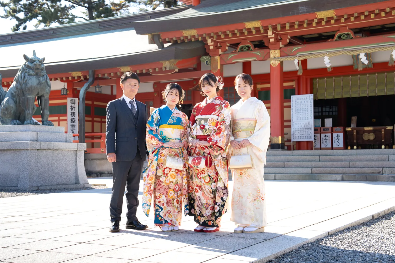 五社神社で、朱色の社殿の前に立つ振袖姿の3人とスーツ姿の男性