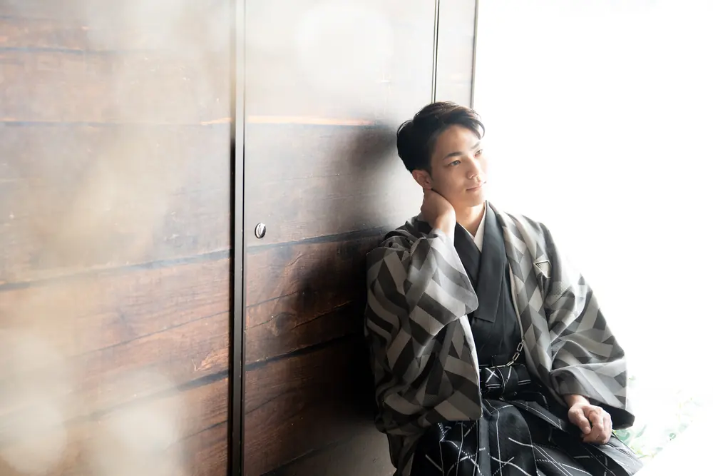 壁にもたれる袴姿の男性