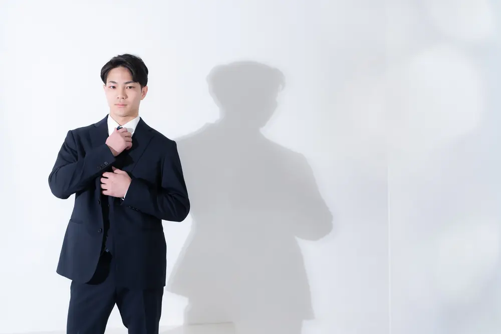 ネクタイに手を添えるスーツ姿の男性