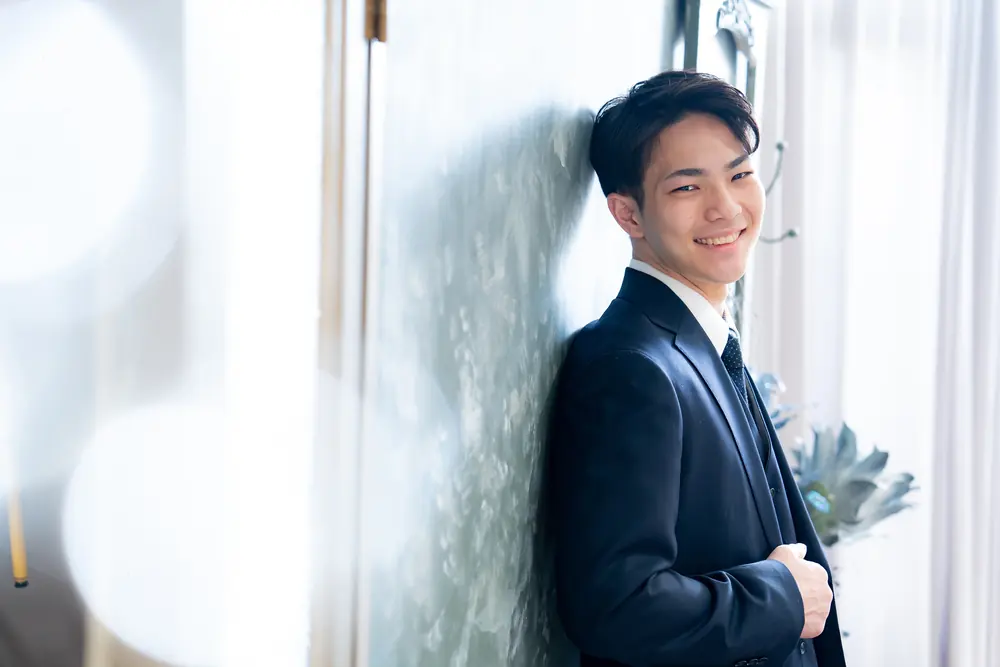 窓辺でほほえむスーツ姿の男性