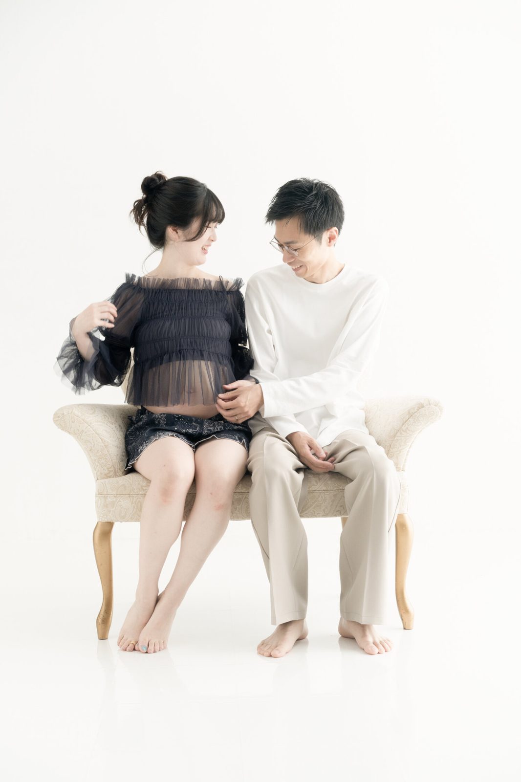 ソファに並んで座る夫婦のマタニティフォト