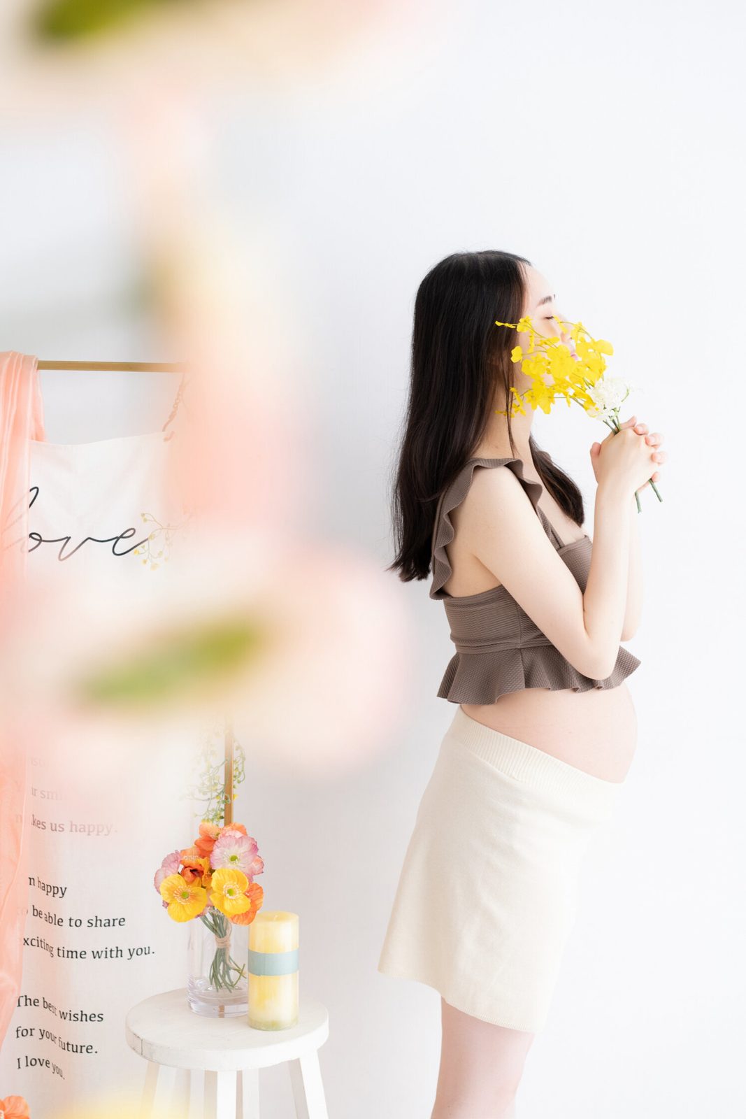 黄色い花を手に横を向く妊婦さん