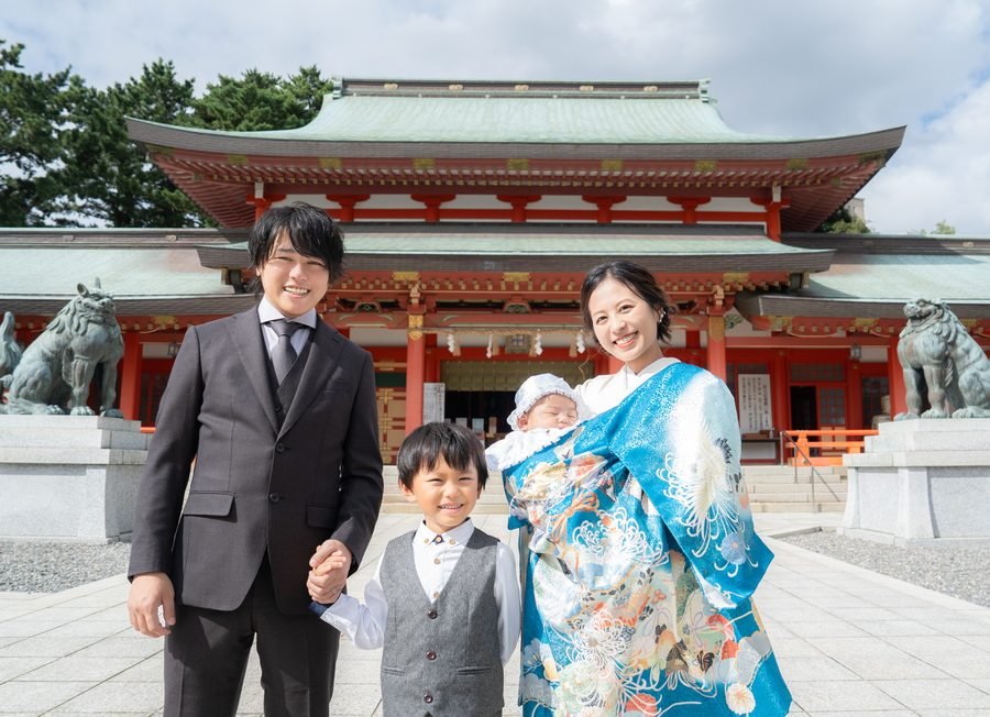 神社で晴れ着姿の赤ちゃんを抱く家族